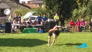 Lucha_leonesa_en_fiestas_de_corona_2_luchadores_caen_al_prado_agarrados_de_fondo_público_mirando_día_soleado_Valle_de_Valdeón