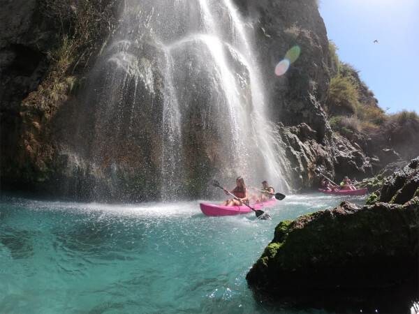 Pareja en kayak pasando debajo de la cascada de Maro Cerro-Gordo en Nerja Malaga